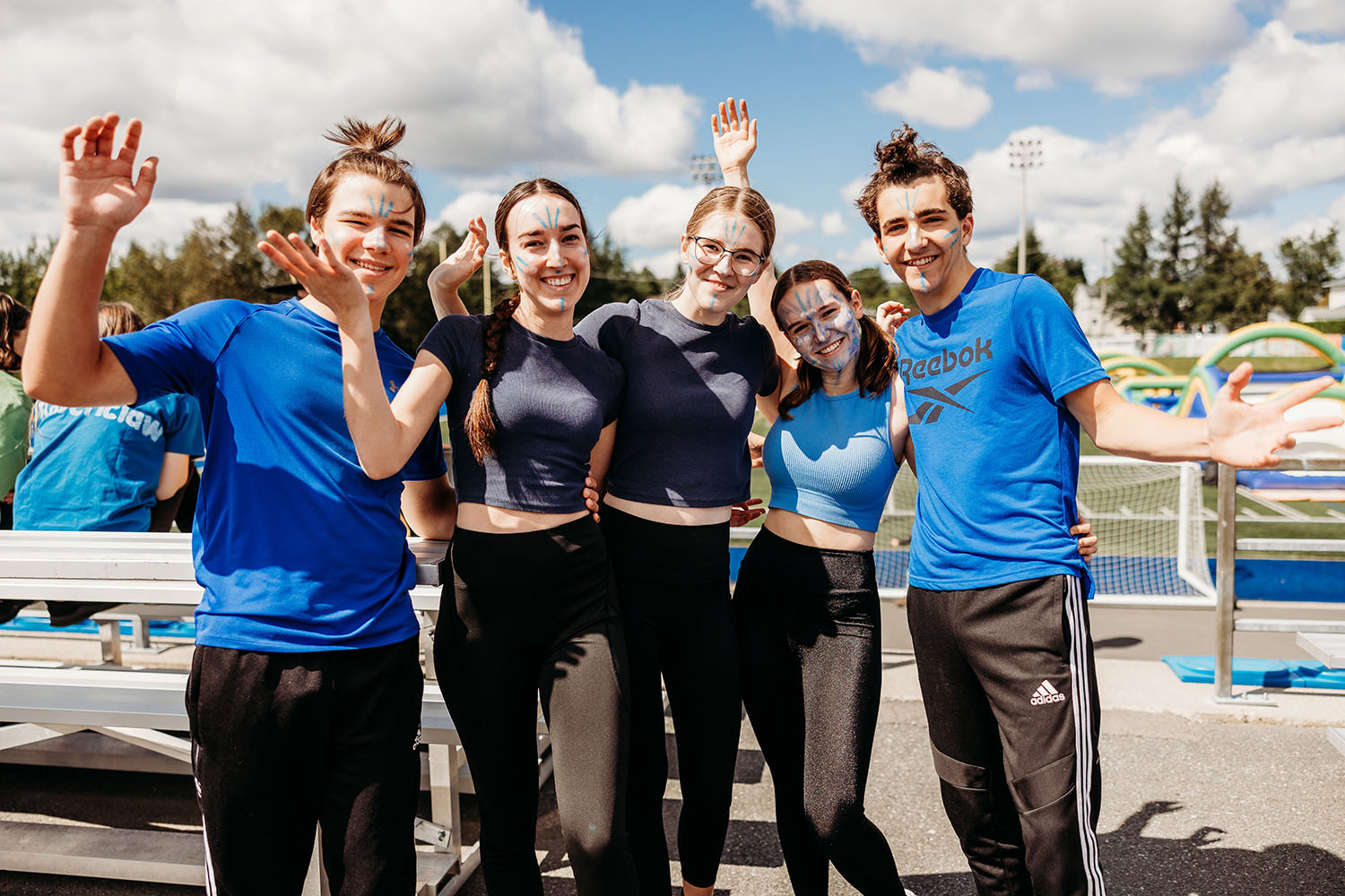 Photo de cinq étudiants, maquillés et souriants à la caméra, à l'extérieur dans le contexte d'un événement social de la vie étudiante collégiale.